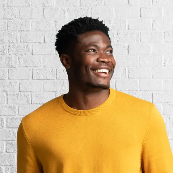 Happy young Black man in a mustard yellow sweater
